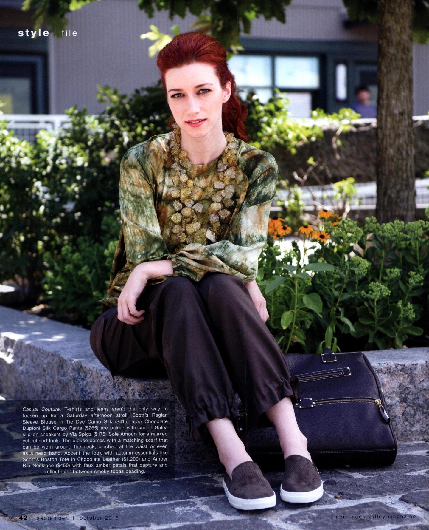 Model wearing Darby Scott apparel and jewelry sitting on the curb outside beside a Darby Scott Boston Tote