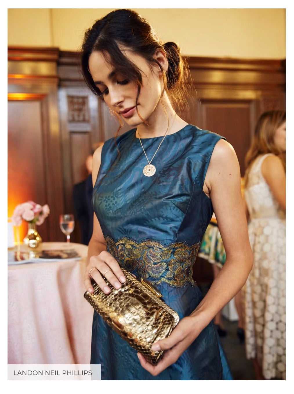 A model dressed in a Darby Scott evening gown and a De Beers Jewellers Necklaces showcases her clutch, also from Darby Scott - Photo Credit Landon Neil Phillips