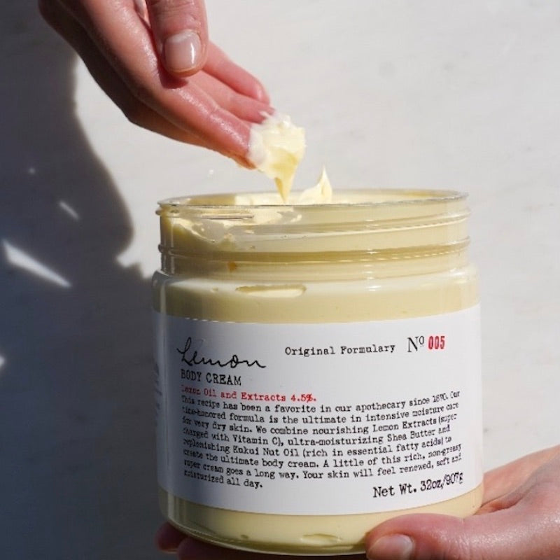 Hand dipping into lemon body cream jar