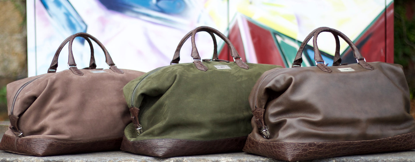Darby Scott's Aspen Duffle Bags on ground in front of a graffiti painted wall