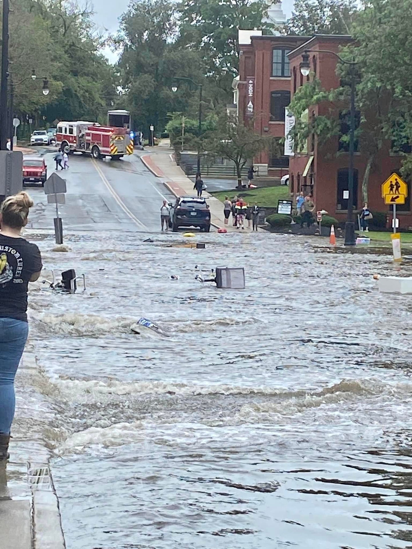 High Street in North Andover with floodwaters and people observing, including a fire truck.
