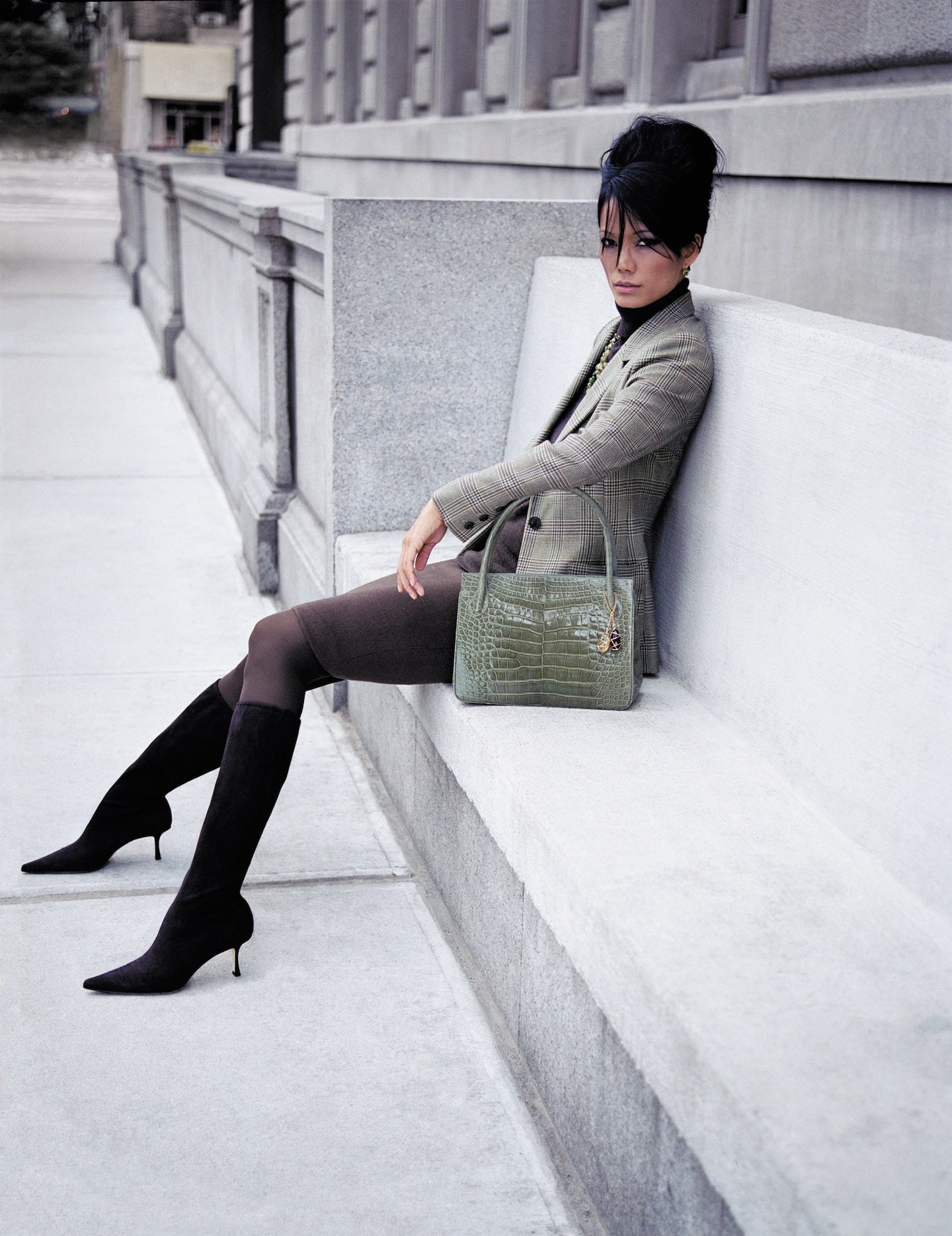 Model sitting on a bench with green alligator Blair Open Tote with trademark gemstone fob accents by Darby Scott