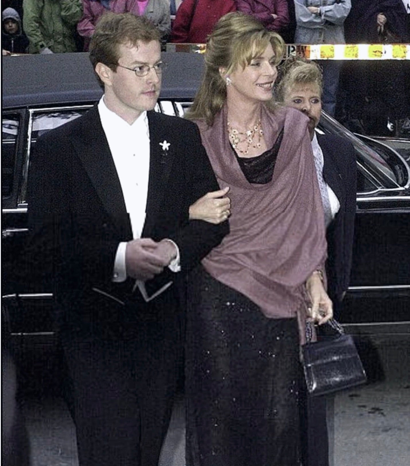 Queen Noor of Jordan, dressed in a gown with shawl draped over her shoulders, and carrying an iconic necklace handle bag by Darby Scott 