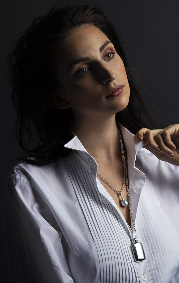 Model wearing a white shirt and sterling silver perfume pendant necklace by Darby Scott