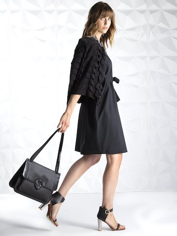 Model wearing black ribbon jacket carrying black saddle style handbag - Darby Scott