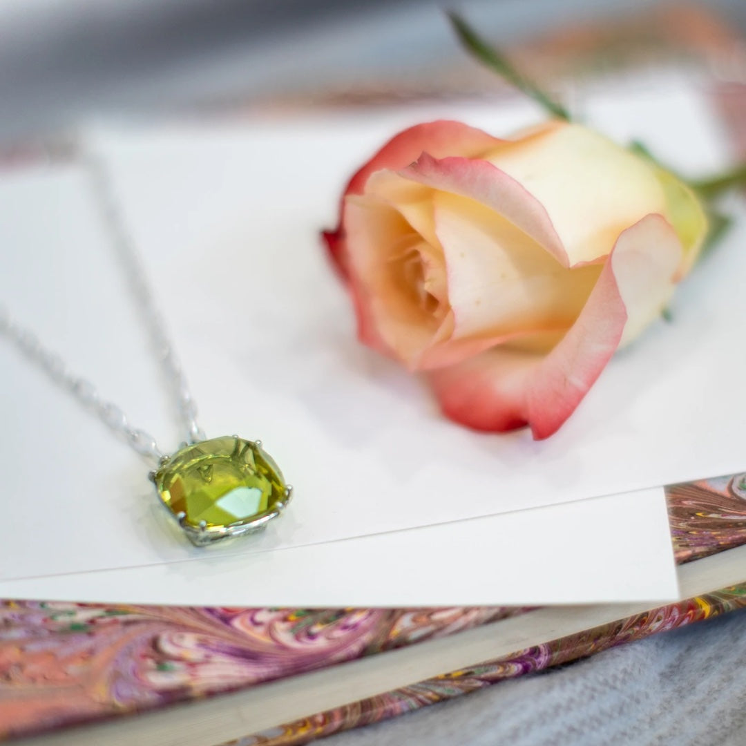 34 Carat Cushion Cut Lime Citrine Pendant by Darby Scott next to a rose