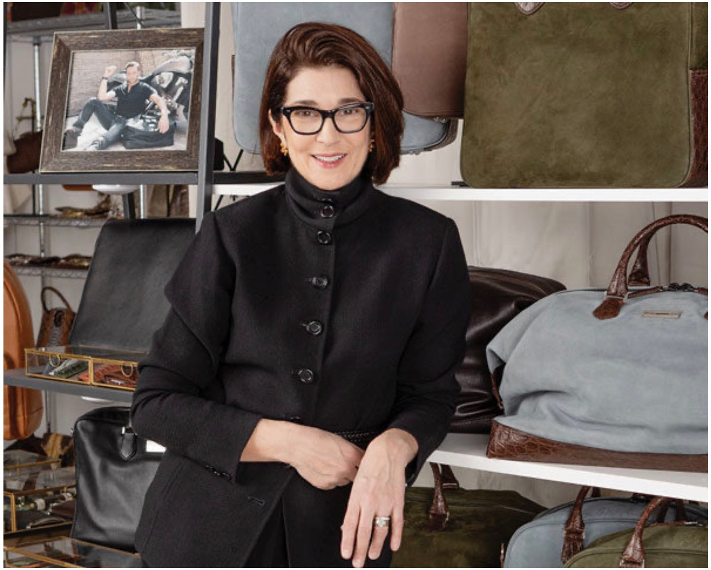 Portrait photograph of Darby Scott in front of a display of her men's collection of travel bags. 