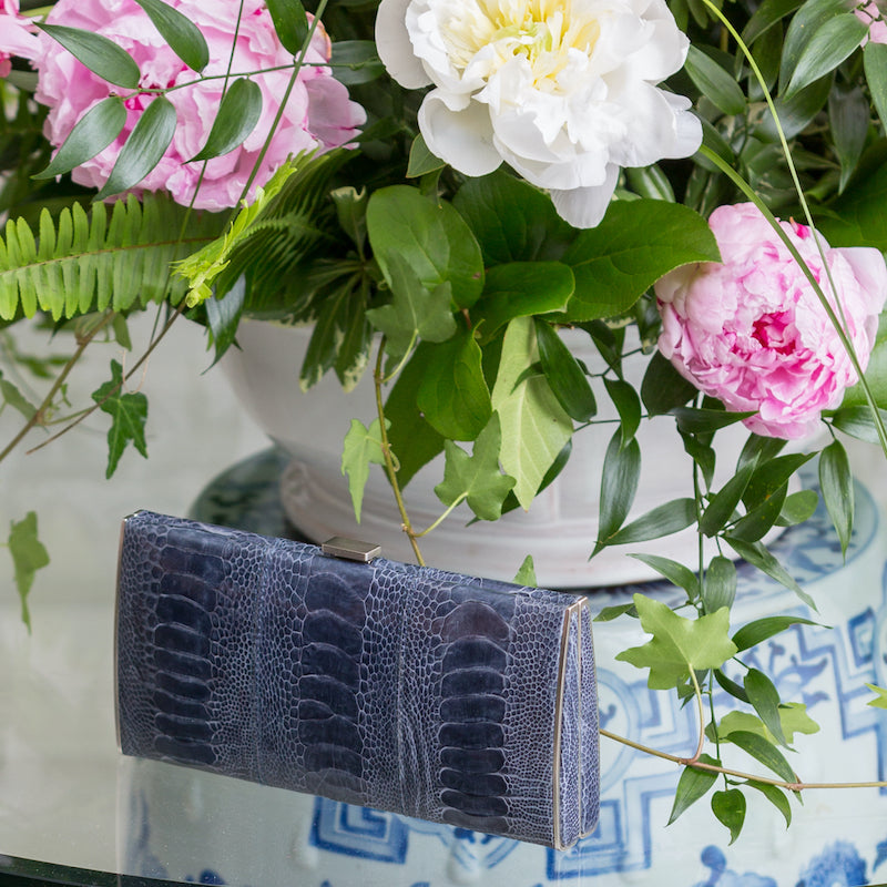 Denim blue box wallet by designer Darby Scott on table with flowers