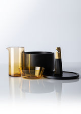 Table set with citrine mixing glass and bowl, dark wood bowl with lid, and brass bottle opener