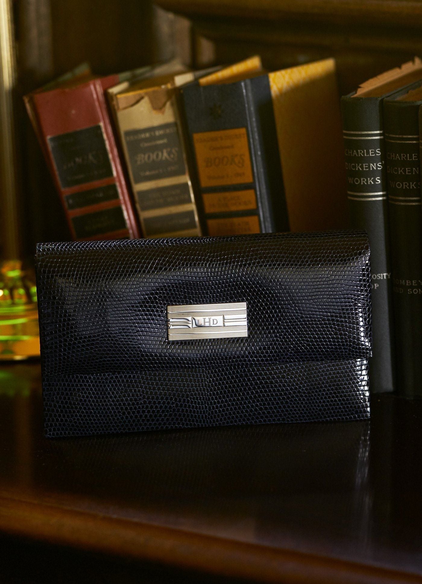 Navy Lizard Mini Monogram Clutch on shelf in front of books- Darby Scott