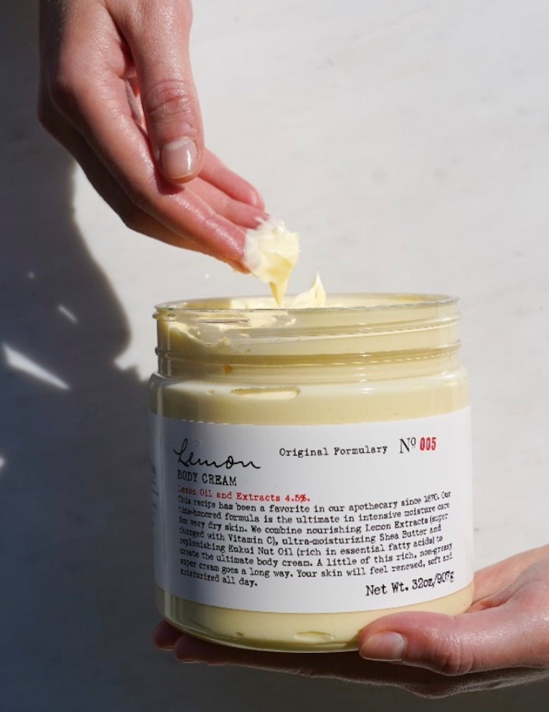 Hand dipping into lemon body cream jar