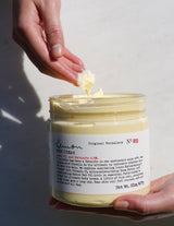 Hand dipping into lemon body cream jar