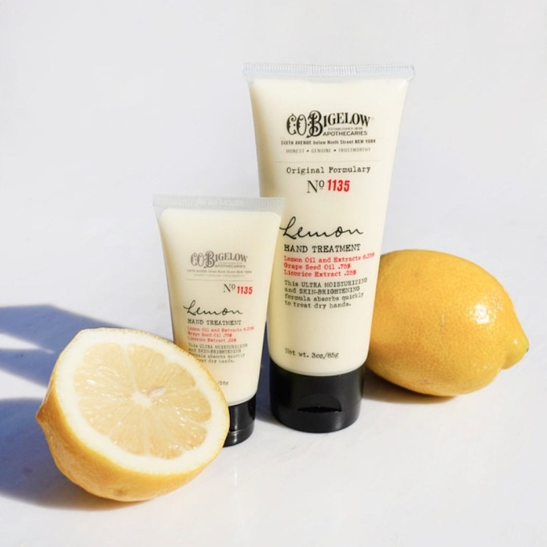 Two tubes of lemon hand treatment beside lemons